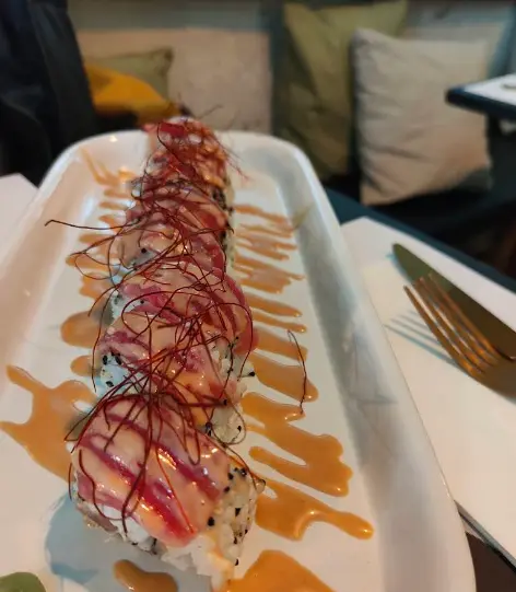 Uramaki de atún en bandeja alargada, cubierto de atún con salsa de tamarindo y filamentos de chile