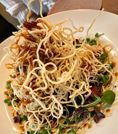 Beef al wok: pappardelle con ternera coronado con fideos de arroz crujientes y brotes verdes